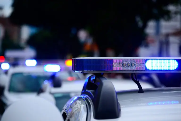 Carro de polícia com sirene ligada policiais criptomoedas Bitcoin
